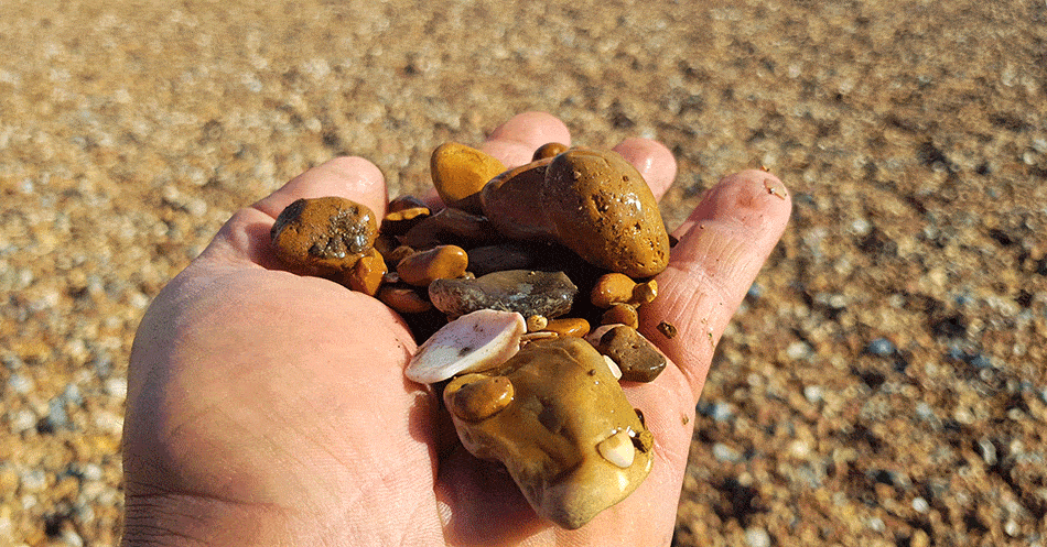 holding a hand full of pebbles over the Pebbles on the beach in Brighton UK
